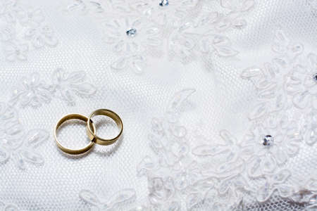 Two wedding rings laying on wedding dressの写真素材