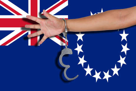 handcuffs with hand on Cook Islands flag