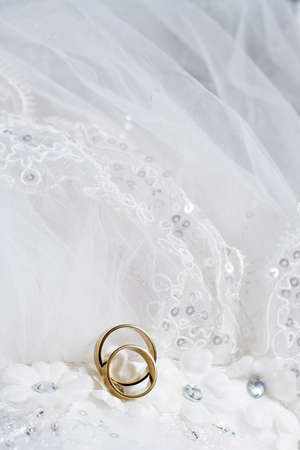 Two wedding rings laying on wedding dressの写真素材