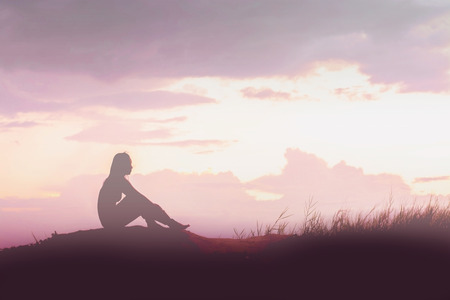 woman silhouette worried on the mountain at sunsetの写真素材