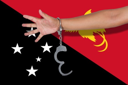 handcuffs with hand on Papau New Guinea flagの写真素材