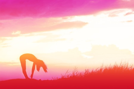 Silhouette Yoga woman in serene sunset at mountainの写真素材
