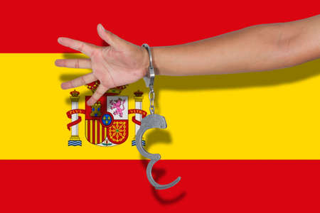 handcuffs with hand on Spain flagの写真素材
