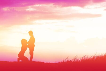 Mother encouraged her son outdoors at sunset, silhouette conceptの写真素材