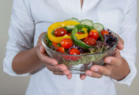 Beautiful woman holding a bowl of fresh veggie saladの写真素材