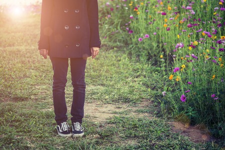 beautiful women wearing black coat, standing in a field of flowers.の写真素材