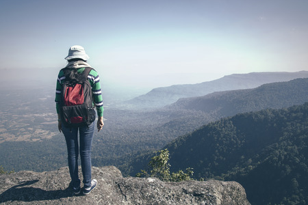 Young woman tourist with backpack standing valley view from top of a mountain
