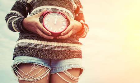 woman hands holding an red alarm clock, time conceptの写真素材
