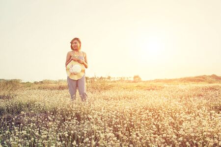 Sexy Beautiful woman standing in flower field and holding her hatの写真素材