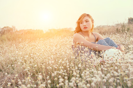 Sad woman sitting in flower field and lonelinessの写真素材