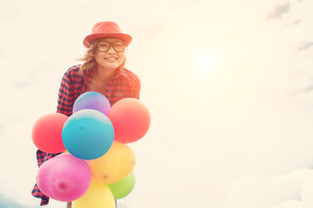 Young hipster woman holding balloons against the blue sky smile to cameraの写真素材