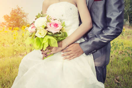 Beautiful bouquet of different colors in the hands of the bride in a white dress , wedding dayの写真素材