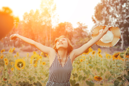 Beautiful sexy raising hands enjoying and smiley with sunflower fieldsの写真素材