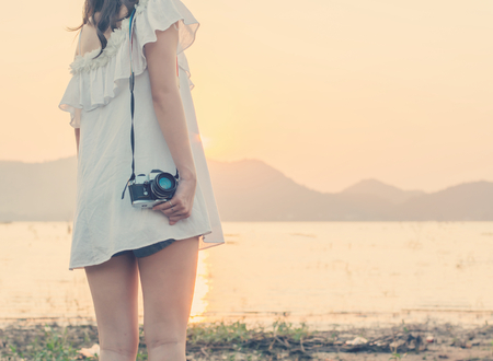 Vintage of beautiful women photography standing hand holding retro camera with sunrise,dream soft styleの写真素材