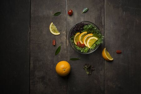Fresh salad with slice of orange on a wooden background