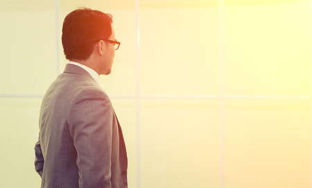 Portrait of serious men boss dressed in luxury elegant clothes watching in window with the sunriseの写真素材