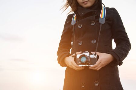 Portrait of a young woman wearing sweater at outdoor carry retro cameraの写真素材