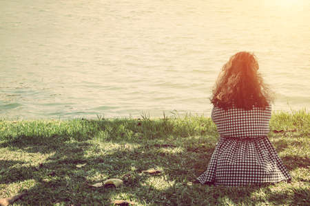 Backside of woman sitting near lake.の写真素材