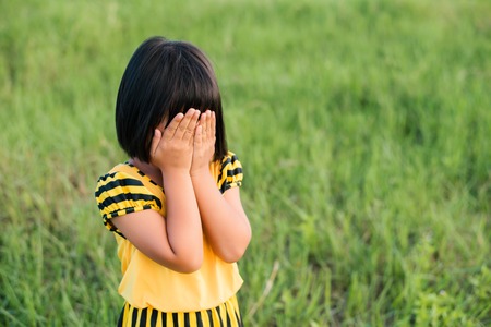 Kids girl bring her hands closed her face and sad.の写真素材