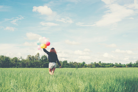 Back of happy young woman standing on green field enjoy with fresh air.の写真素材