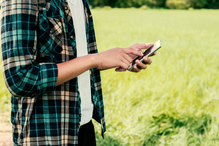 Close-up of hipster man hands using his smartphone outdoor in the park.の写真素材