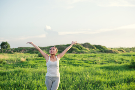Happy beautiful woman with stretched arms in meadows with fresh air.の写真素材