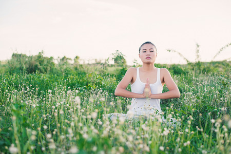 healthy and beautiful young yoga  woman sitting with joined hands at meadows.の写真素材