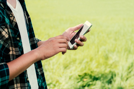 Close-up of man hands using his smartphone outdoor in the park.の写真素材