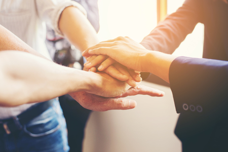 Concept of teamwork: Close-Up of hands business team showing unity with putting their hands...