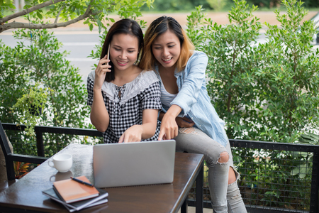 two young beautiful women searching information at laptop computer in cafe.の写真素材