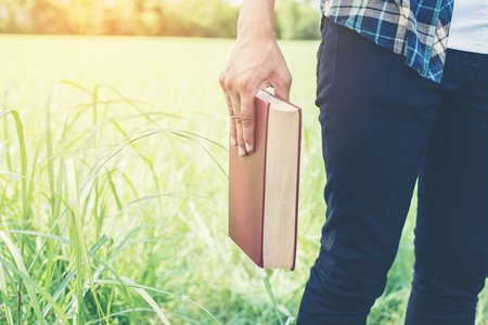 Man hands holding books on green meadow.の写真素材