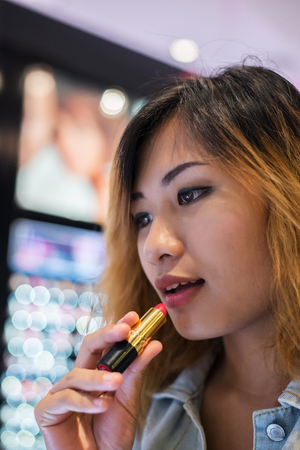 Beautiful young woman select color lipstick to buying at shopping mall.の写真素材