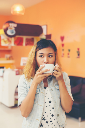 Young beautiful woman drinking hot cappuccino coffee at cafe.の写真素材