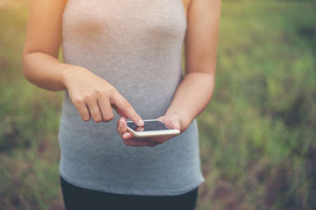 Young woman hands typing smartphone in the park.の写真素材