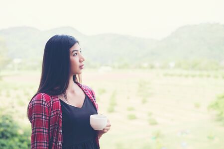 Portrait of the beautiful woman holding a cup of coffee in the morning,mountain view behind.