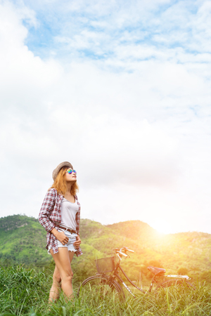 Beautiful hipster woman standing on a green meadow with nature and mountain background,Relaxing concept.の写真素材