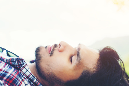 Happy young hipster lying on bench in the nature park.の写真素材