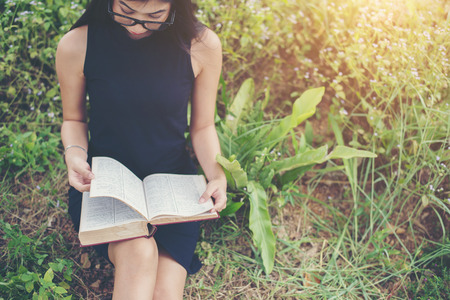Relaxed young beautiful woman reading a book at the lawn with sun shining.の写真素材
