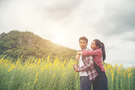 Young hipster couple relaxing in yellow flower field at summer. Enjoying with nature.の写真素材