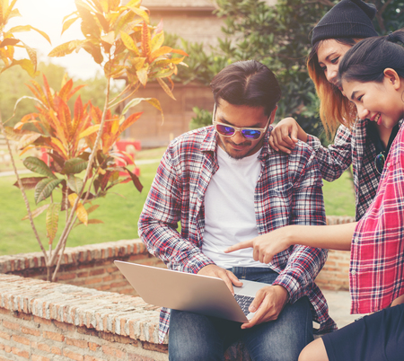 Group of young hipster teenager using laptop outdoor in summer holiday have fun and take time together.の写真素材