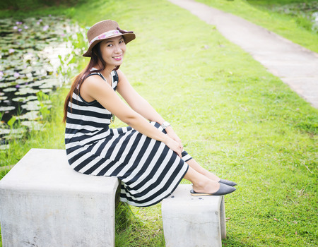 young beautiful woman sitting on bench in green park.の写真素材