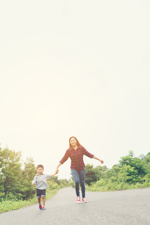 Little boy holding his mother hand running on the street enjoy good time together look so nice.の写真素材