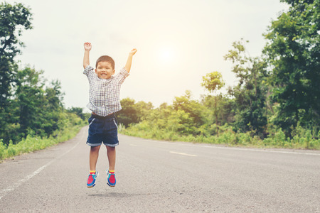 Cute little asian boy jumping on the road.の写真素材