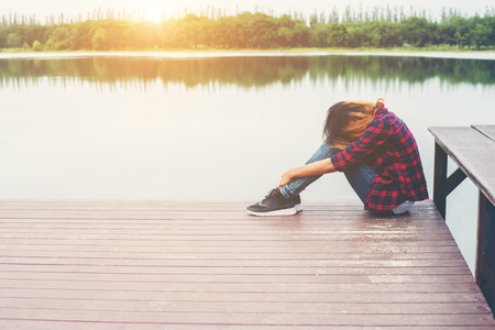 Sad hipster woman sitting on the pier with sadness.の写真素材