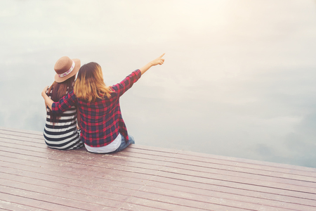 friendship,two women sit on the pier,Relaxing spending good time together.の写真素材