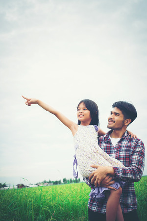 Daughter pointing away and smiling with her dad in the meadows field.の写真素材