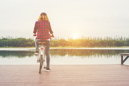 Back of young hipster woman cycling with bicycle on a pier,Relaxing enjoy summer holiday.の写真素材
