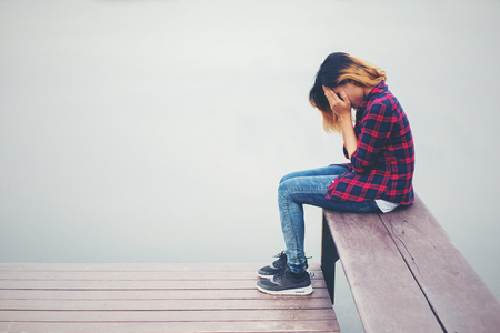 Sad hipster woman sitting on the pier with sadness.の写真素材