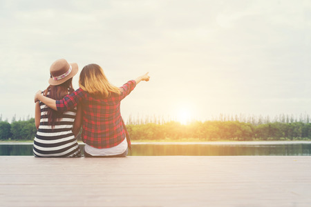 friendship,two women sit on the pier,Relaxing spending good time together.の写真素材