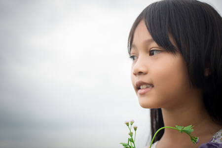 Portrait of Little cute asian girl holding flower among the purple flower field look at the camera, freedom enjoy concept.の写真素材